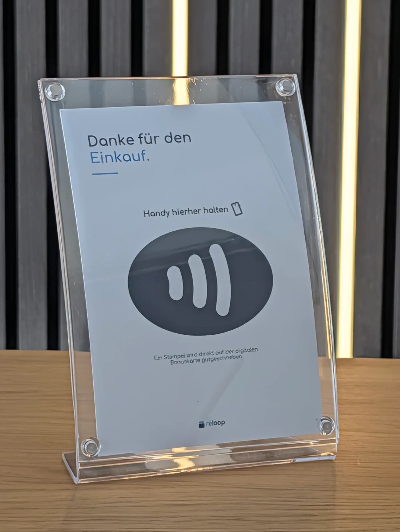 Smartphone wird an einen reloop NFC-Aufsteller an der Kasse gehalten